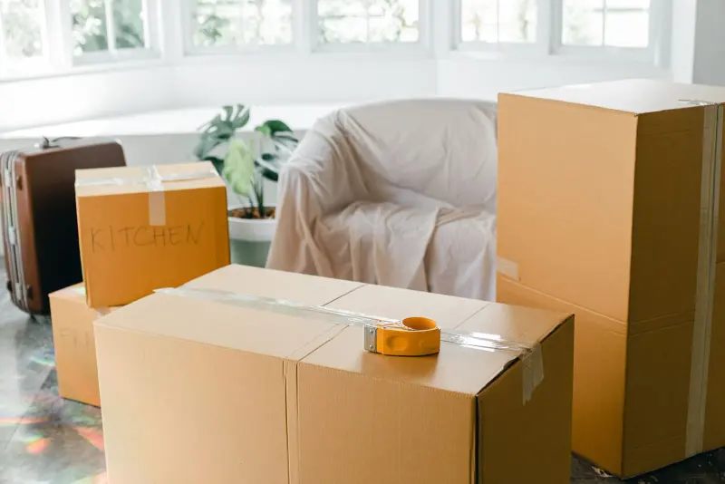 Packed cardboard boxes and a suitcase in a bright room before a move