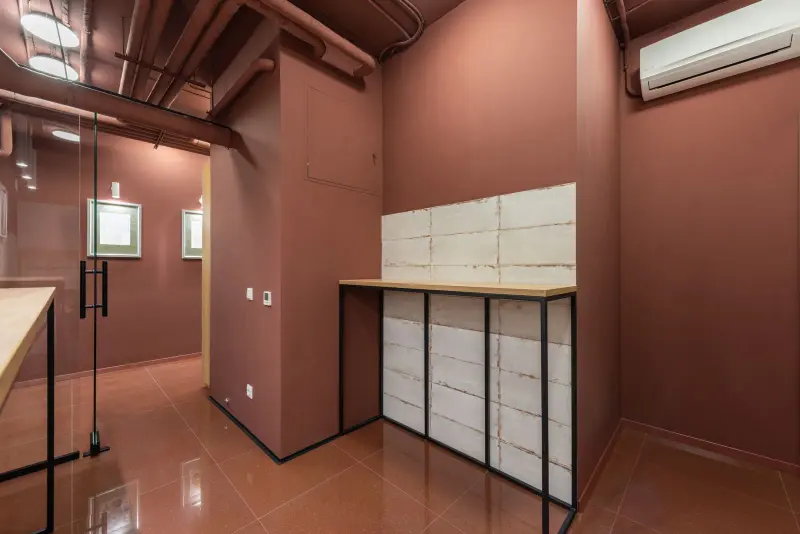 Small, empty modern office with warm terracotta walls and a glass door