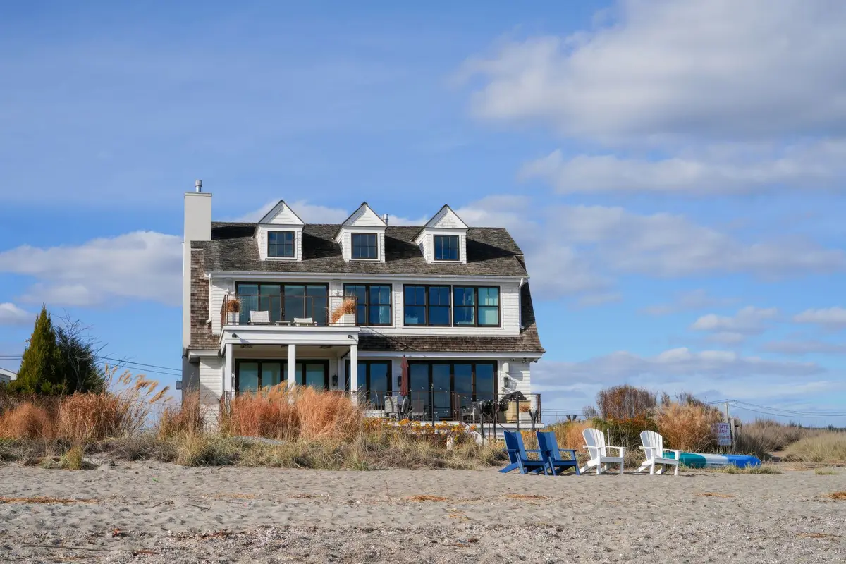 Shingled beach house among dune grasses under a blue sky